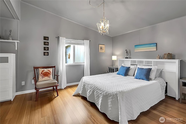 bedroom with an inviting chandelier, baseboards, crown molding, and wood finished floors