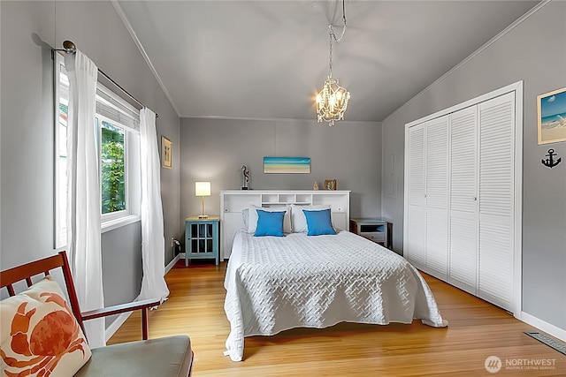 bedroom featuring visible vents, wood finished floors, baseboards, a chandelier, and ornamental molding