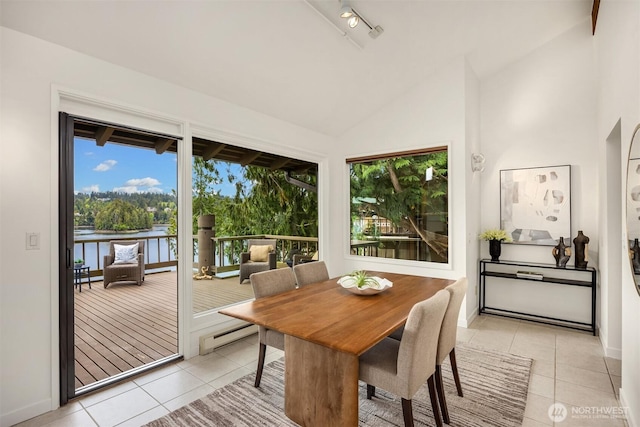 dining room with high vaulted ceiling, baseboards, light tile patterned floors, a water view, and a baseboard heating unit