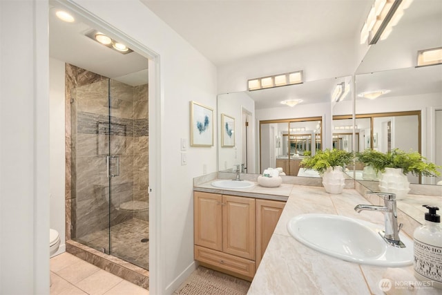 bathroom with tile patterned flooring, a sink, a stall shower, and toilet