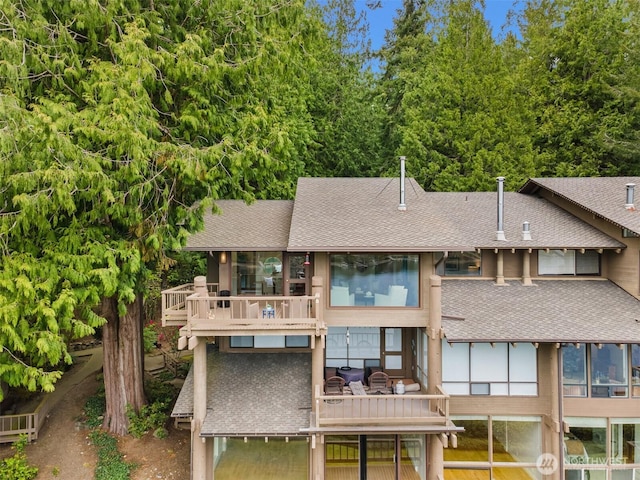 rear view of property featuring a shingled roof and a balcony