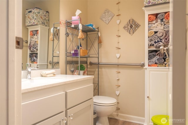 bathroom featuring toilet, baseboards, and vanity