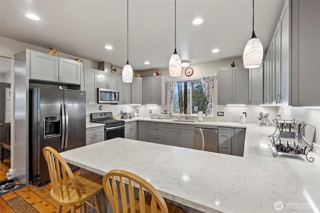 10871 Alfred St, Rockport, WA 98283 - kitchen featuring a sink, a peninsula, light stone counters, gray cabinetry, and appliances with stainless steel finishes