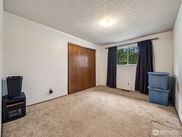 unfurnished bedroom with a textured ceiling, visible vents, carpet, and a closet