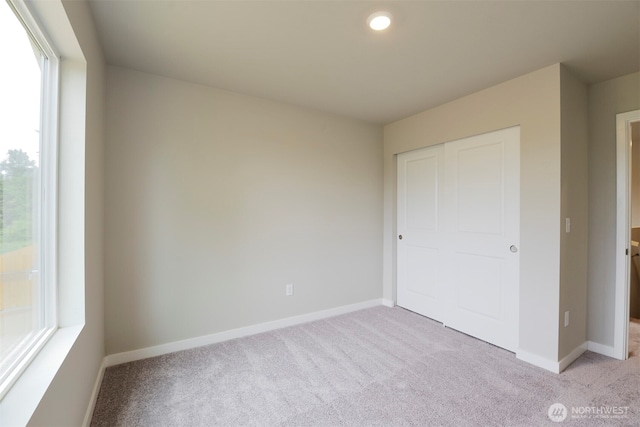 unfurnished bedroom featuring a closet, baseboards, and light carpet