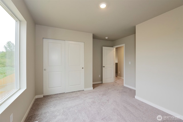 unfurnished bedroom featuring a closet, baseboards, and light carpet