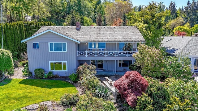 rear view of property featuring a yard, a balcony, a chimney, and board and batten siding
