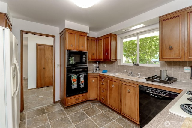 kitchen with black appliances, a sink, brown cabinetry, and backsplash