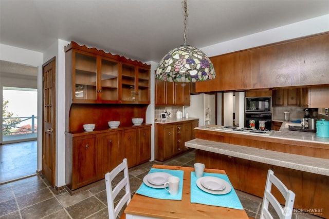 kitchen featuring brown cabinetry, black appliances, light countertops, a peninsula, and backsplash