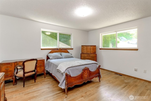 bedroom featuring light wood finished floors and a textured ceiling
