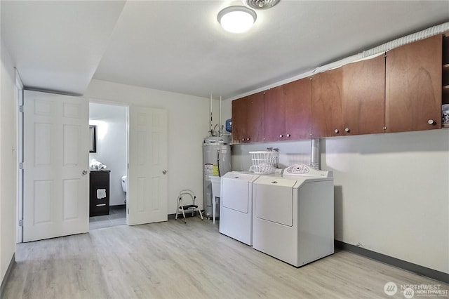 washroom featuring cabinet space, washing machine and dryer, light wood-style floors, and water heater