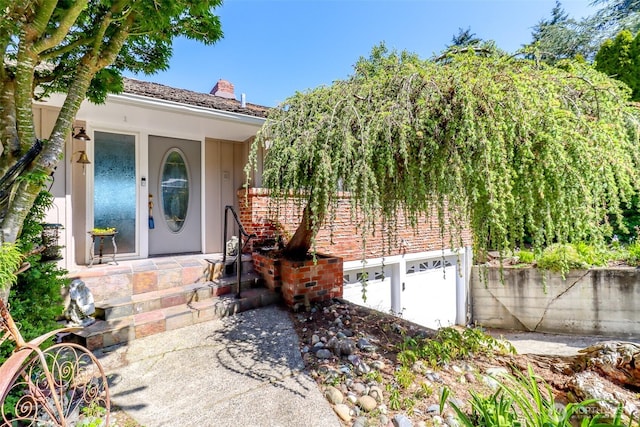 entrance to property featuring stucco siding, a chimney, and covered porch