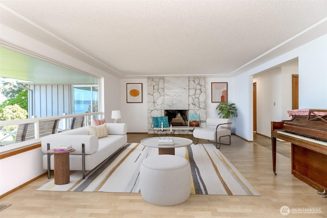 living room featuring a textured ceiling, a fireplace, wood finished floors, and baseboards