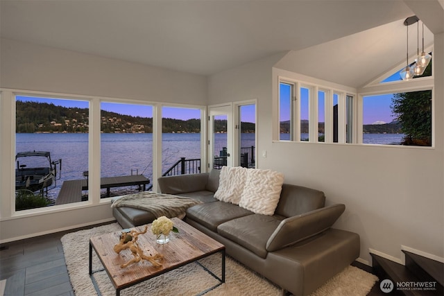 living room with a water view, dark wood-style flooring, baseboards, and plenty of natural light