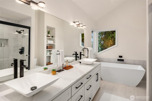 bathroom featuring a shower stall, lofted ceiling, a soaking tub, and a sink