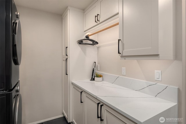 kitchen with stacked washer and clothes dryer, white cabinetry, and light stone counters