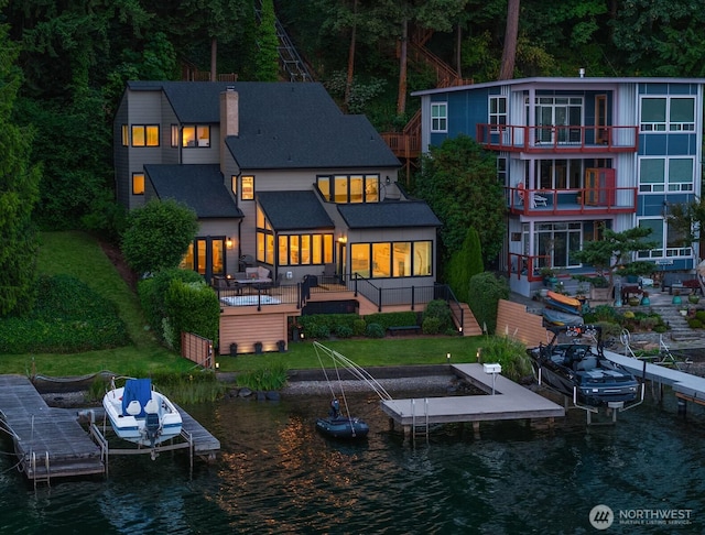 back of property featuring boat lift, a yard, a water view, and a chimney