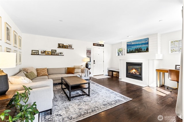 living area featuring plenty of natural light, a fireplace with flush hearth, and dark wood-style floors