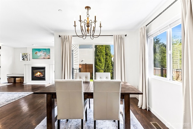 dining room featuring a glass covered fireplace, plenty of natural light, dark wood-type flooring, and a notable chandelier