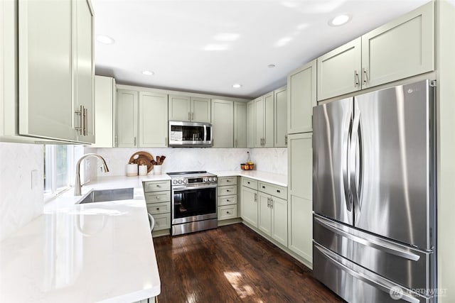 kitchen with backsplash, appliances with stainless steel finishes, a sink, recessed lighting, and dark wood-type flooring