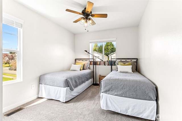 carpeted bedroom featuring baseboards, ceiling fan, and visible vents