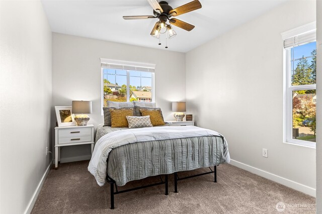 carpeted bedroom featuring baseboards, multiple windows, and a ceiling fan