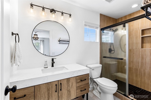 bathroom featuring vanity, a shower stall, toilet, and visible vents