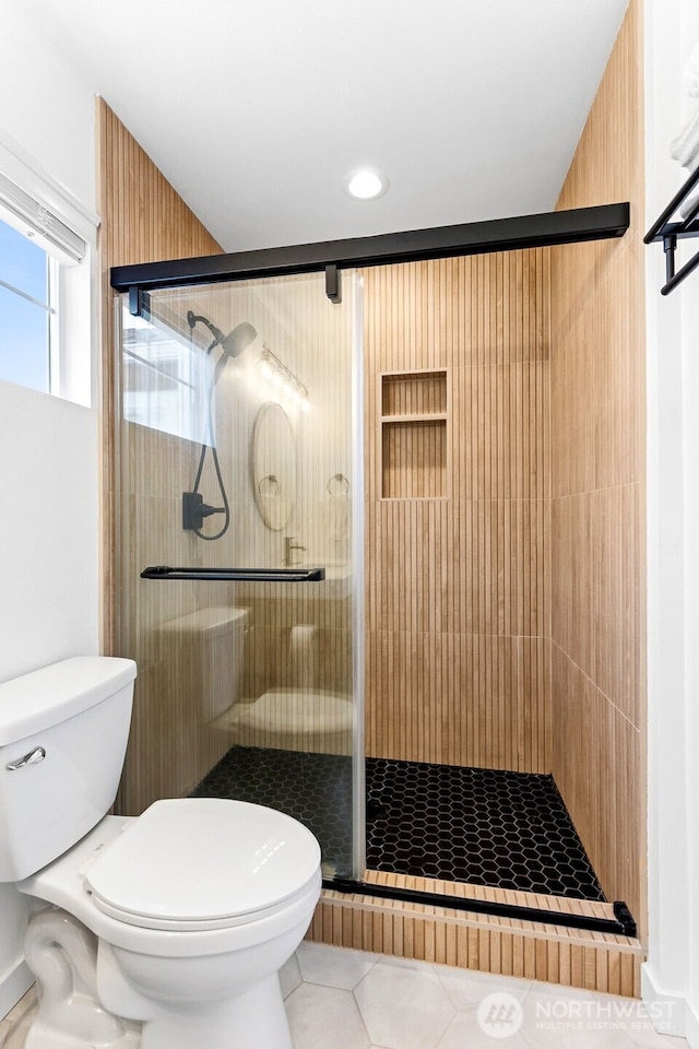 full bathroom featuring toilet, a shower stall, and tile patterned flooring