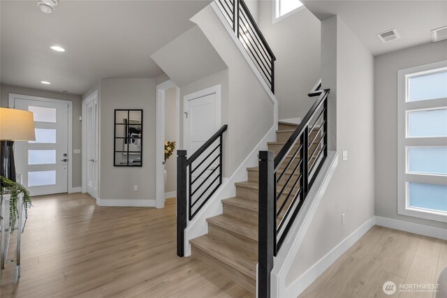 stairway with baseboards, recessed lighting, wood finished floors, and visible vents