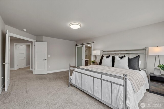 carpeted bedroom with baseboards and a barn door