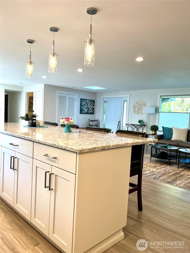 2940 161st Ave SE, Bellevue, WA 98008 - kitchen featuring white cabinets, hanging light fixtures, light wood-style floors, light stone counters, and recessed lighting