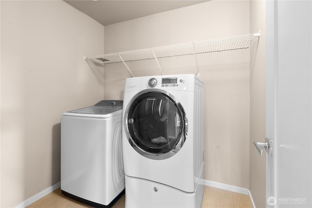 clothes washing area with washer and dryer, laundry area, and baseboards
