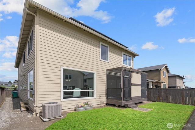 back of property featuring a lawn, central AC, and a fenced backyard