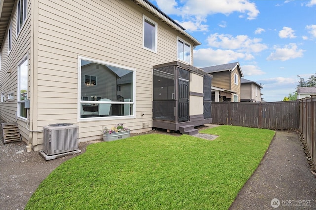 rear view of property featuring a yard, cooling unit, and a fenced backyard