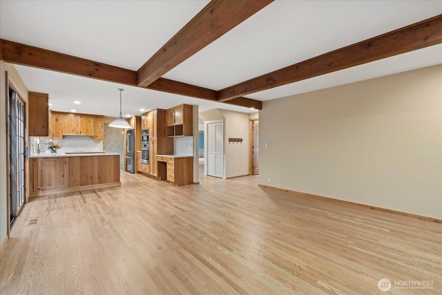 kitchen featuring open floor plan, recessed lighting, light wood finished floors, appliances with stainless steel finishes, and beamed ceiling