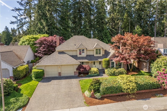 traditional home with an attached garage, driveway, and brick siding