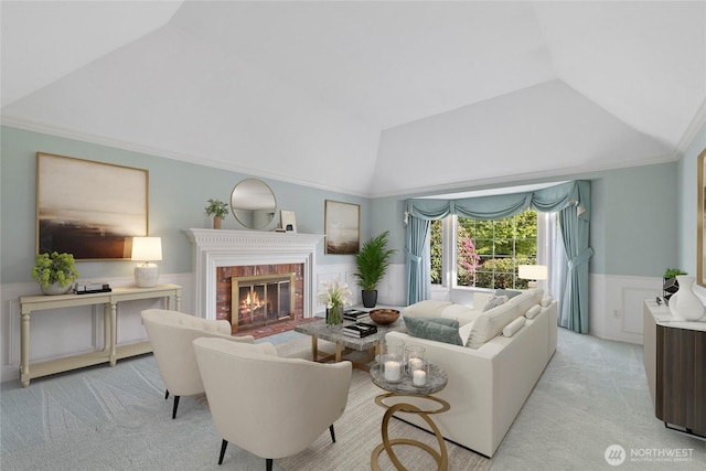 living area with light colored carpet, lofted ceiling, a wainscoted wall, a fireplace, and crown molding