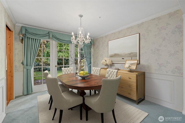 dining room featuring light carpet, a chandelier, crown molding, a wainscoted wall, and wallpapered walls
