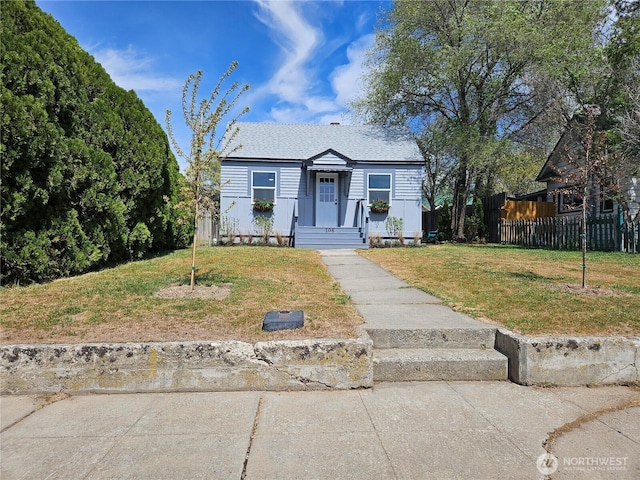 bungalow-style house with fence and a front lawn