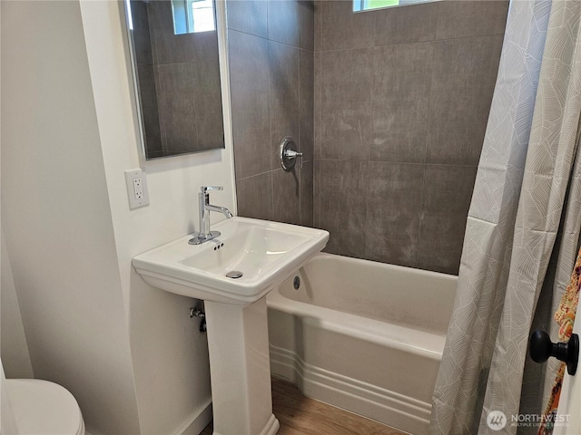 bathroom with toilet, wood finished floors, and shower / tub combo
