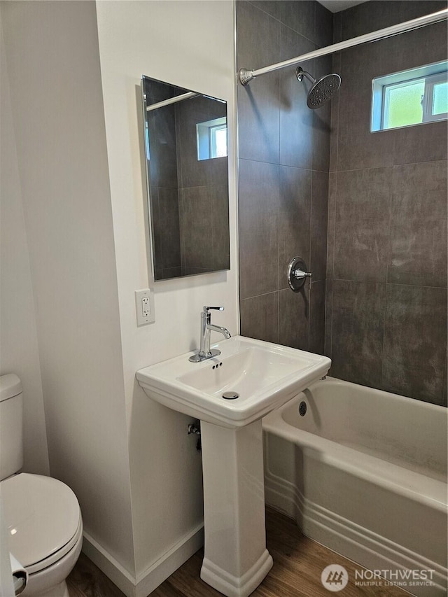 bathroom with wood finished floors, bathing tub / shower combination, and toilet