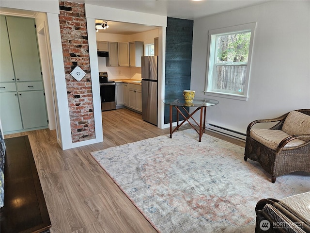 interior space featuring appliances with stainless steel finishes, baseboard heating, light wood finished floors, light countertops, and under cabinet range hood