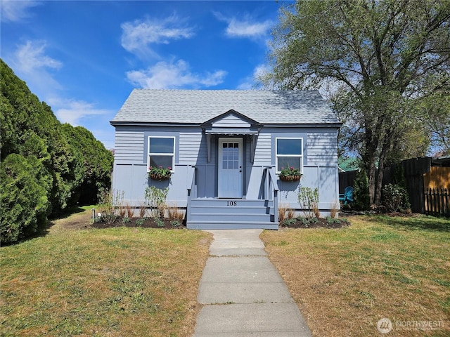 bungalow featuring a shingled roof, fence, and a front yard
