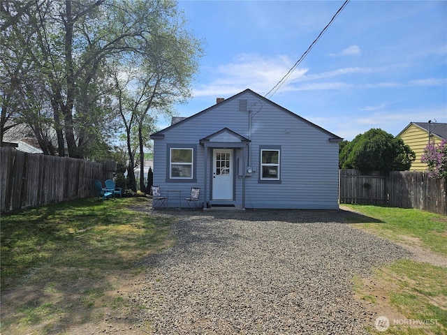 bungalow featuring a fenced backyard, a front lawn, and a chimney