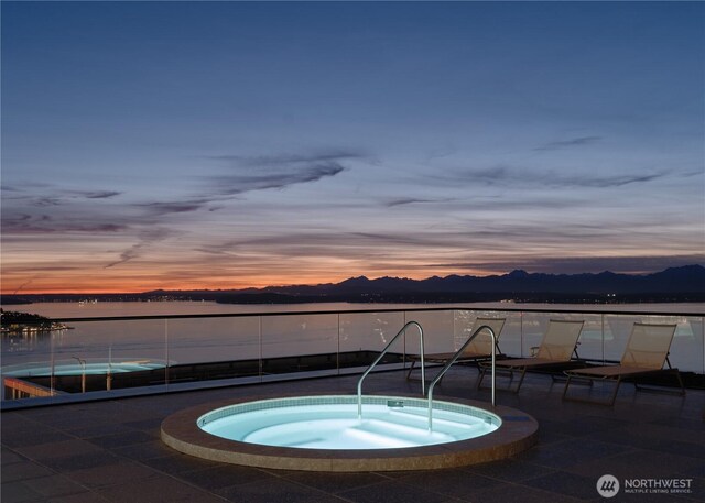 view of swimming pool featuring a water view and a hot tub