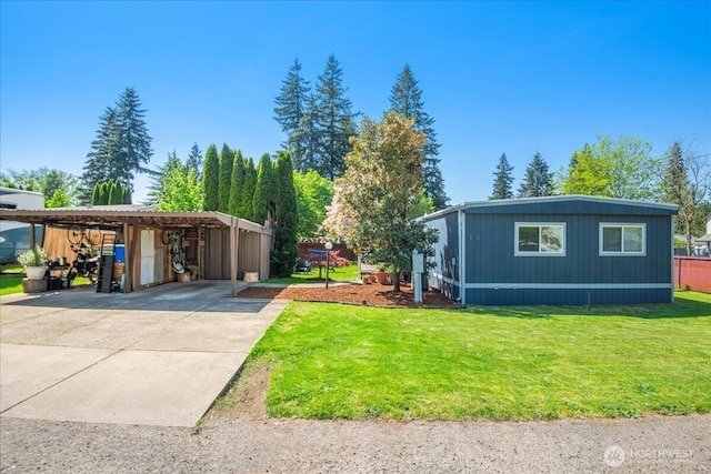 view of front facade featuring a detached carport, an outbuilding, a front yard, and concrete driveway