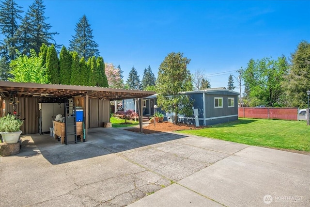 view of front of house featuring a front lawn, fence, an outbuilding, and concrete driveway