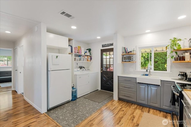 kitchen with open shelves, freestanding refrigerator, gray cabinets, black electric range, and independent washer and dryer