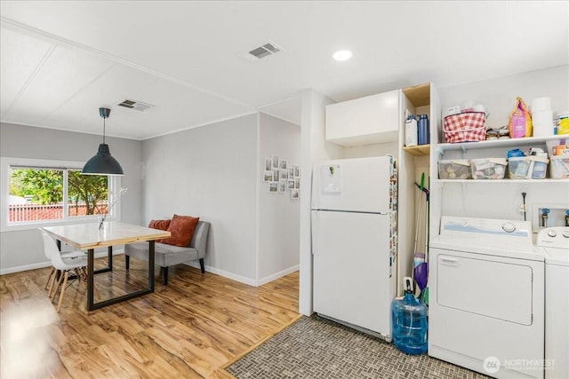 interior space featuring visible vents, freestanding refrigerator, open shelves, washer and dryer, and light wood-type flooring