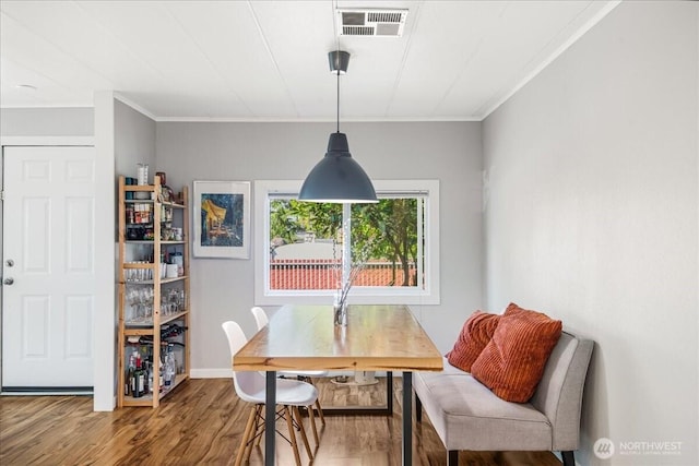 dining space featuring visible vents, ornamental molding, baseboards, and wood finished floors